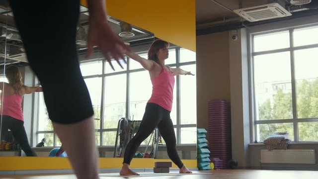 Yoga in fitness club - coach shows fitness exercise for women, modern gym