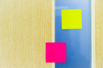 Yellow and pink reminder sticky note on board, empty space for text with light from window.