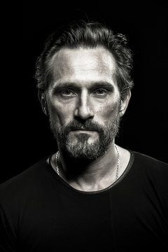 Monochrome portrait of strong mature beardy man. Male with severe look on his face.
