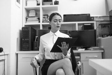 Business woman sitting in office and examining documents.