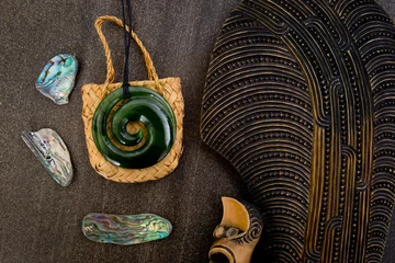 Fototapeten New Zealand - Maori themed objects - mere, greenstone and woven kite bag with shells © CreativeFire
