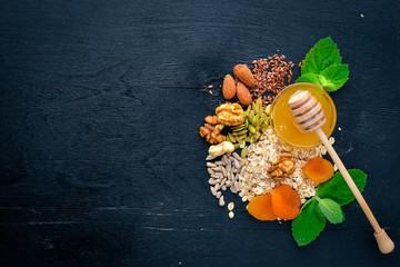 Healthy food. Honey, nuts, oatmeal, dried fruits and dried apricots, flax, sunflower seeds. On a wooden background. Top view. Free space for text.