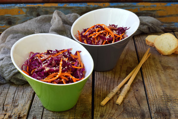 Salad of purple or red cabbage and carrots sprinkled with sesame seeds on a wooden background. Healthy and vegetarian food