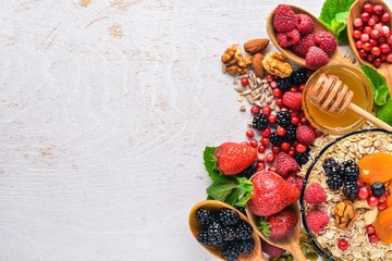 Healthy food. Fresh wild berries, copper, nuts, oatmeal, dried fruits and seeds. On a wooden background. Top view. Free space for text.