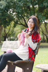 秋の公園で編物をする女性