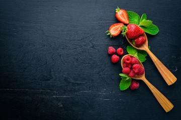 Assortment of berries. Raspberries, blackberries, strawberries, cranberries. On a wooden background. Top view. Free space for text.