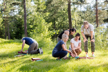 Friends Arranging Building Blocks On Grassy Field