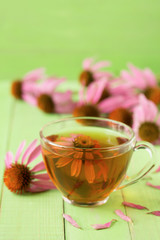 Cup of echinacea tea on green wooden table