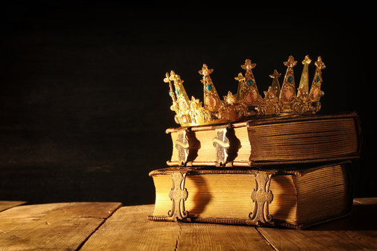 low key of queen/king crown on old books. vintage filtered. fantasy medieval period