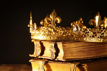low key of beautiful queen/king crown on old books. vintage filtered. fantasy medieval period