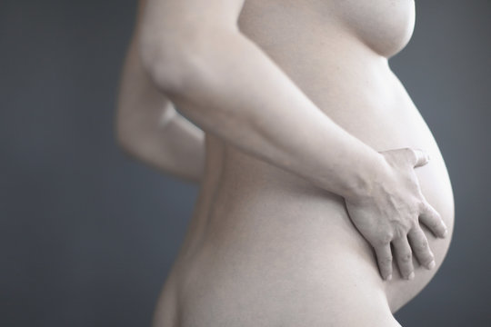 naked pregnant woman touching her stomach