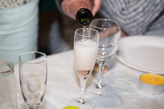 man serves a glass of pink champagne during party