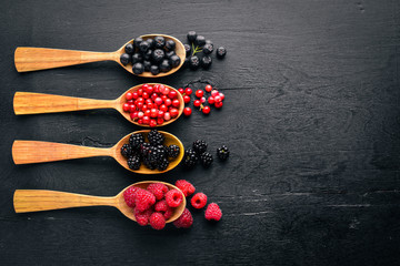 Assortment of berries. Raspberries, blackberries, strawberries, cranberries. On a wooden background. Top view. Free space for text.