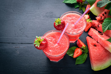 Fresh cocktail of watermelon and strawberries. Mint, ice. On a wooden board. Top view. Free space...