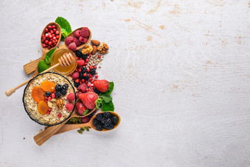 Healthy food. Fresh wild berries, copper, nuts, oatmeal, dried fruits and seeds. On a wooden background. Top view. Free space for text.