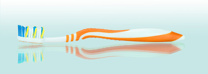 Оранжево белая зубная щетка на зеркальном фоне