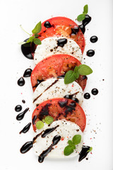 Italian Caprese salad with Mozzarella Tomato Oregano Black Pepper and Balsamic Vinegar on White...