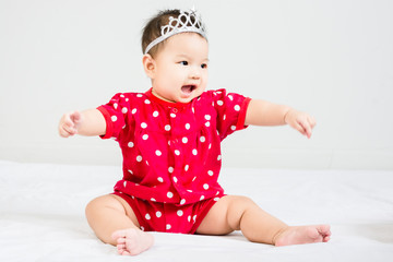 Portrait of adorable  baby sitting on a white floor with crown