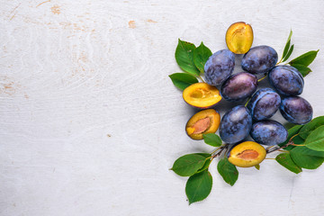 Plums with green leaves. On a wooden background. Top view. Free space for text.