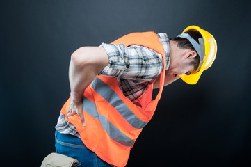 Constructor holding back  and bending over like hurting - obrazy, fototapety, plakaty