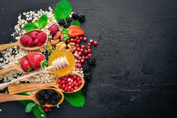 Healthy food. Fresh wild berries, copper, nuts, oatmeal, dried fruits and seeds. On a wooden background. Top view. Free space for text.