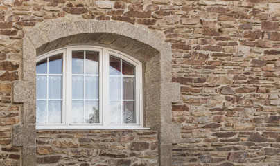 Schönes Bogenfenster aus weißem PVC mit 3 Flügeln in Fassade aus Naturstein in Granit - Beautiful arched window in white PVC with 3 wings in natural stone facade in granite