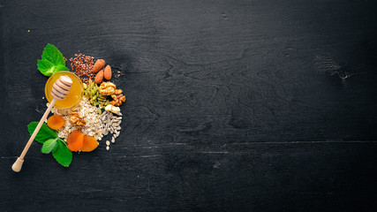 Healthy food. Honey, nuts, oatmeal, dried fruits and dried apricots, flax, sunflower seeds. On a...