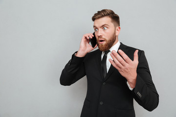 Surprised bearded man talking on his smartphone and looking away