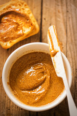 Almond butter in bowl with crackers on wooden table 