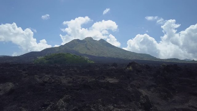 AERIAL CLOSE UP Flying above rough stony black lava terrain and grey ashy volcanic soil at the toot of the Mount Batur mountain range in Bali, Indonesia. Dramatic landscape at Kintamani volcano crater