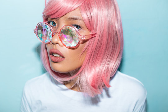 Asian pink hair woman portrait with kaleidoscope glasses and unicorn queen shirt