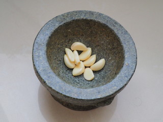 Peeled garlic are in rock martar