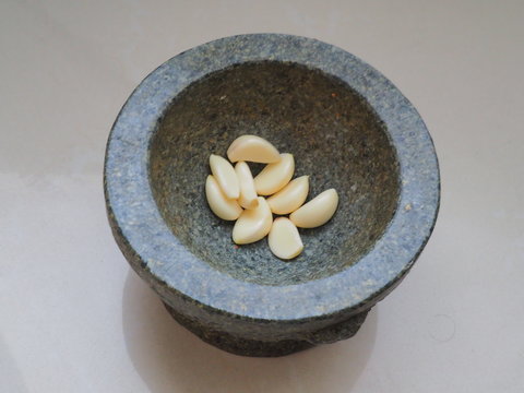 Peeled garlic are in rock martar