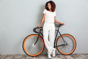 Full length image of Smiling african woman posing with bicycle