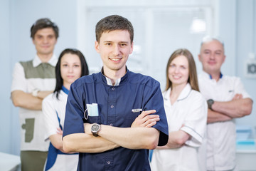 Group of dentists standing in their office and looking at camera.
