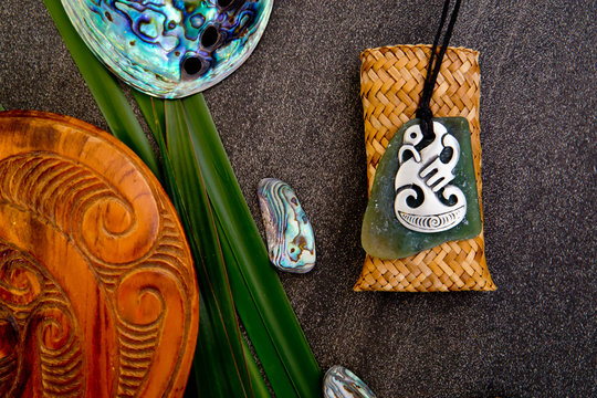 New Zealand - Maori themed objects - metal and greenstone pendant, wooden mere with flax leaves and abalone shells