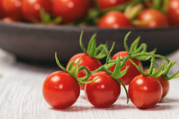 Fresh cherry tomato on white wood table. Close up lovely cherry tomato for background or wallpaper. Prepare fresh cherry tomato for home cooking look so delicious. Side view, macro concept.