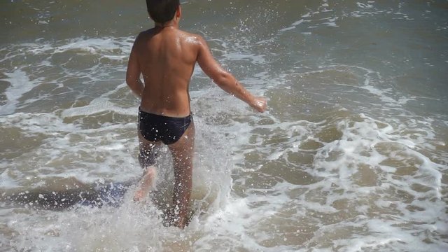 Healthy boy jumping to the sea from beach