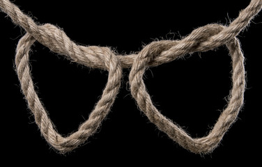Rope forms two heart in a knot. Isolated on black background. With copy space text. Studio Shot.