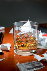 whiskey with ice on an expensive office Desk on the background of torn contract