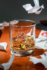 whiskey with ice on an expensive office Desk on the background of torn contract