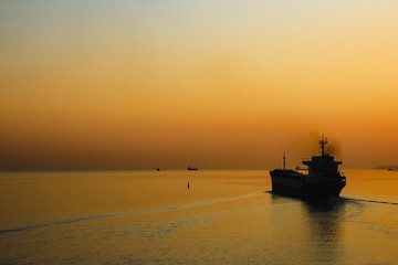 Obraz premium Cargo ship on sea in the rays of the setting sun.