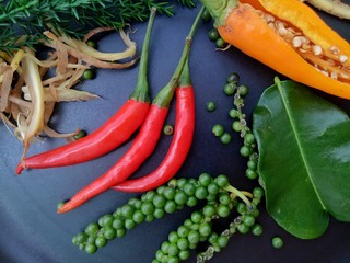 Close up red hot spicy chili with composition of tropical spices on black plate background, selective focus