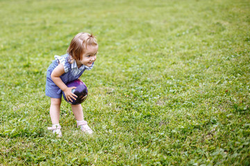 Little girl playing with ball on grass in a Park