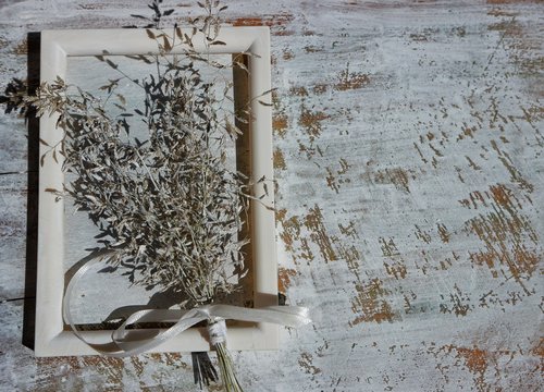 The white wooden fraime with a bouquet of herbs lying on a white wooden  plank