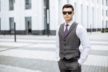 A young man in a suit and sunglasses outdoors in the city