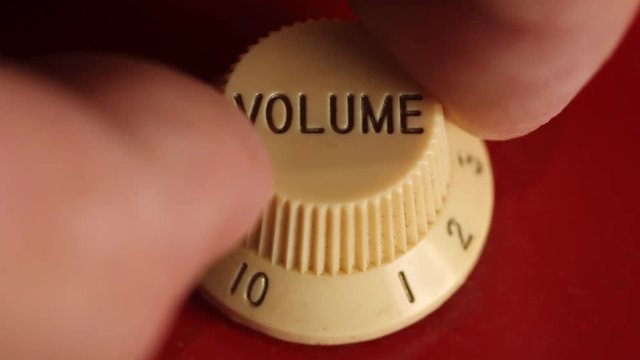 Cranking Up The Volume Knob On An Electric Guitar.