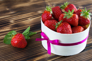 Strawberries in the wooden box on the brown background 
