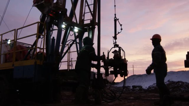 Camera Shows Worker Silhouettes Operating with Equipment