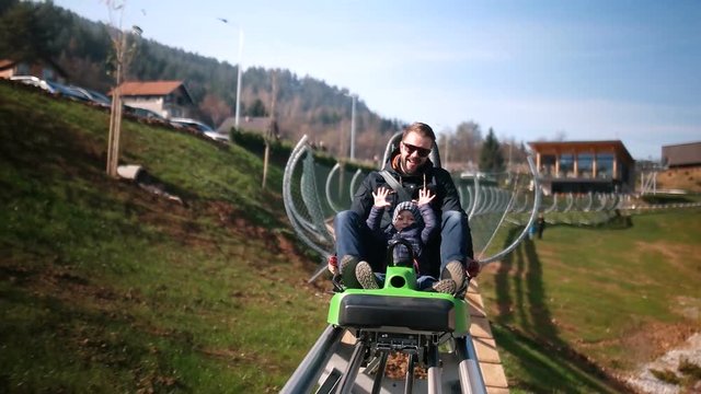 Father and son enjoying while riding forest roller coaster